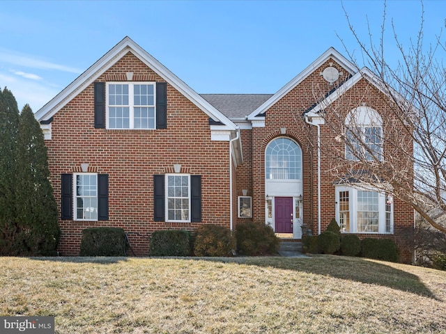 traditional home with a front lawn and brick siding