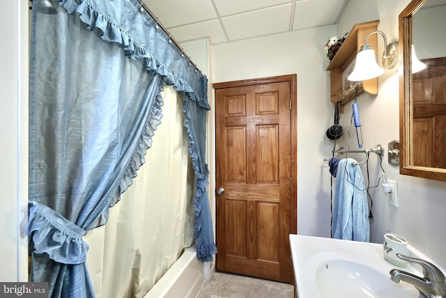 bathroom with a paneled ceiling, shower / tub combo, and sink