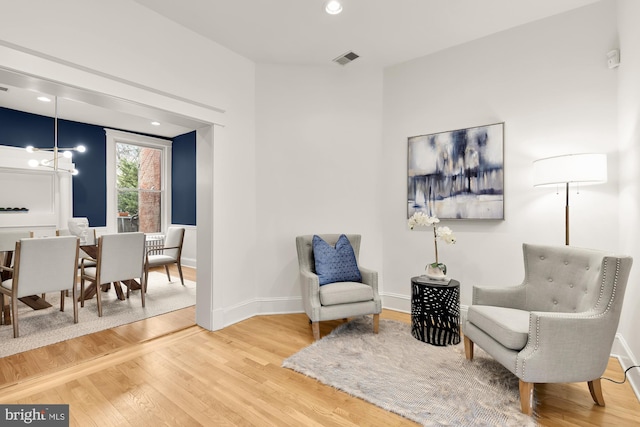 sitting room featuring a chandelier, visible vents, baseboards, and wood finished floors