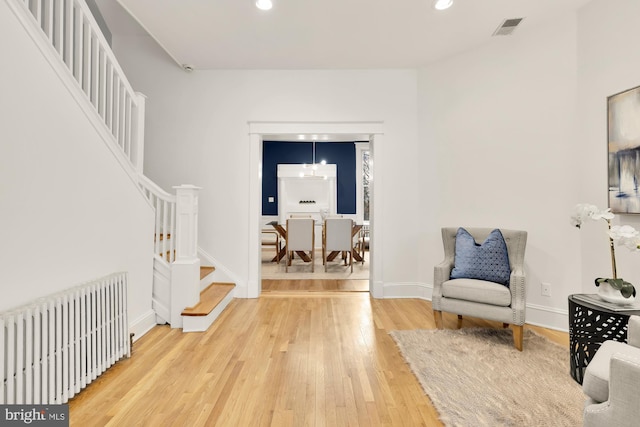 living area featuring visible vents, radiator, wood finished floors, stairs, and recessed lighting