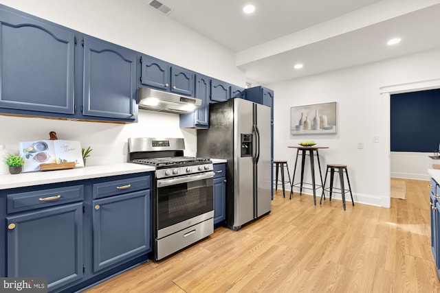 kitchen with under cabinet range hood, blue cabinetry, stainless steel appliances, and light countertops