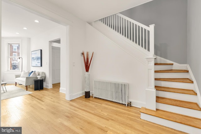 stairs featuring radiator heating unit, recessed lighting, wood finished floors, and baseboards