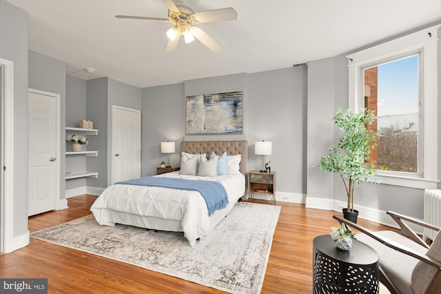 bedroom with radiator, ceiling fan, baseboards, and wood finished floors