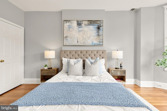 bedroom featuring wood finished floors, visible vents, and baseboards