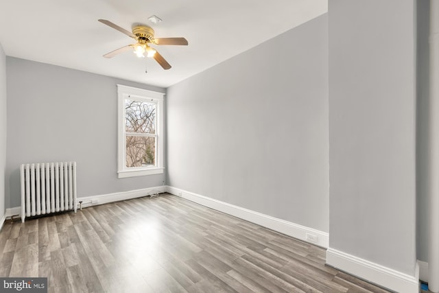 empty room featuring light wood-type flooring, radiator heating unit, baseboards, and ceiling fan