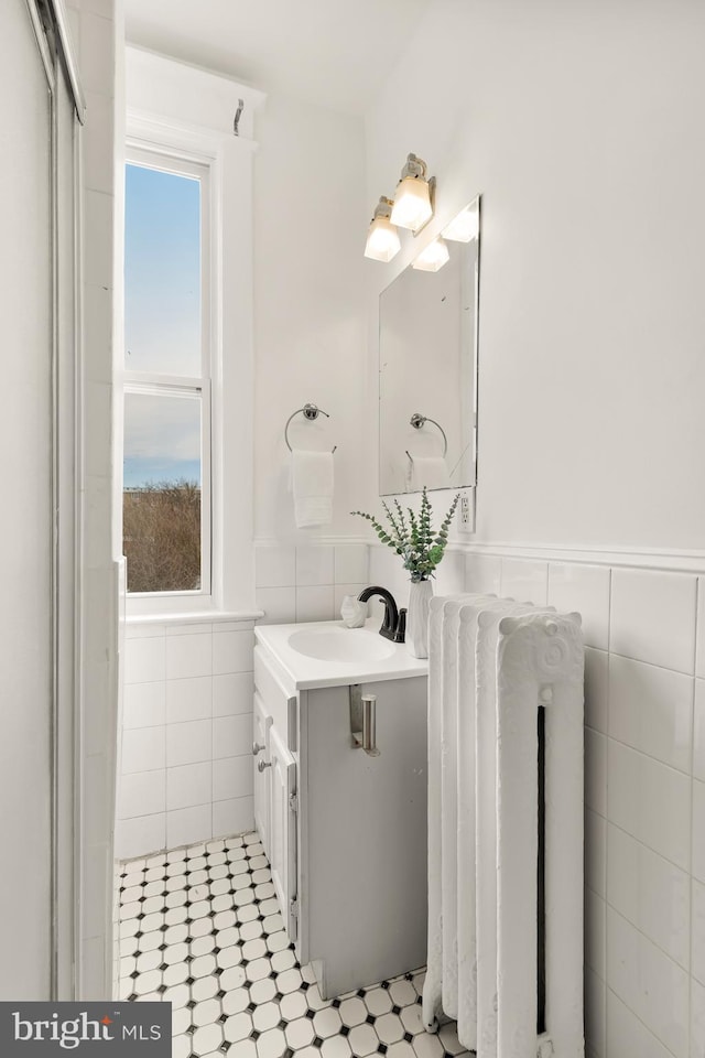 bathroom featuring radiator, vanity, tile walls, and wainscoting