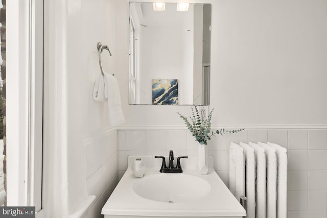 bathroom with wainscoting, radiator heating unit, tile walls, and vanity