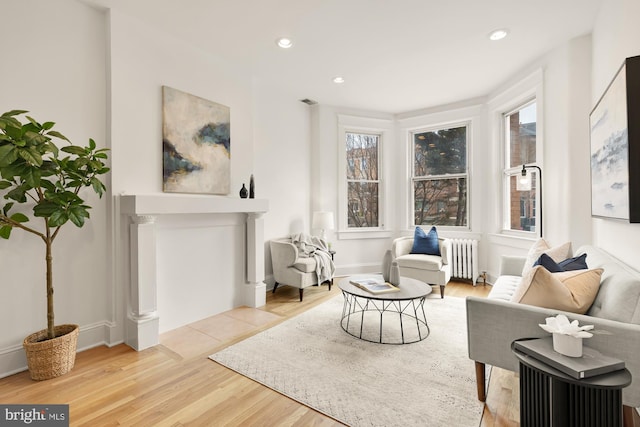 sitting room featuring light wood-style floors, recessed lighting, radiator, and baseboards