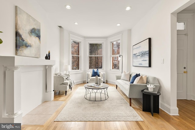 living area featuring recessed lighting, visible vents, radiator heating unit, light wood-style floors, and baseboards