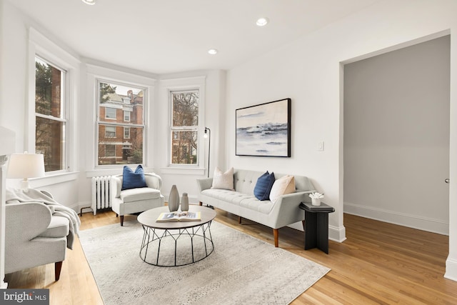 living room featuring radiator heating unit, baseboards, wood finished floors, and recessed lighting