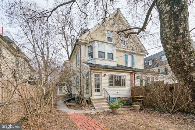 back of house featuring entry steps, fence, and stucco siding