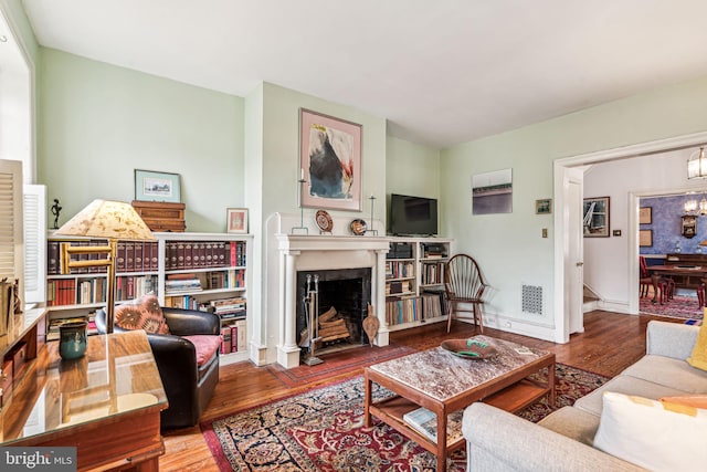 living room featuring baseboards, a fireplace, visible vents, and wood finished floors