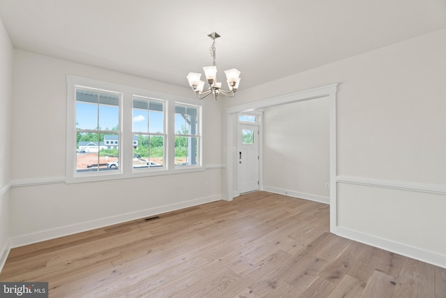 unfurnished dining area featuring light wood-type flooring and a chandelier