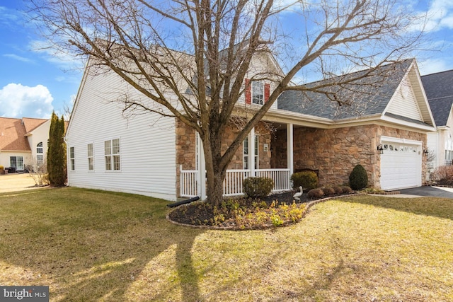 view of side of home with a yard, covered porch, and a garage