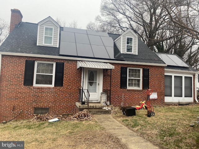 cape cod-style house featuring a front yard and solar panels