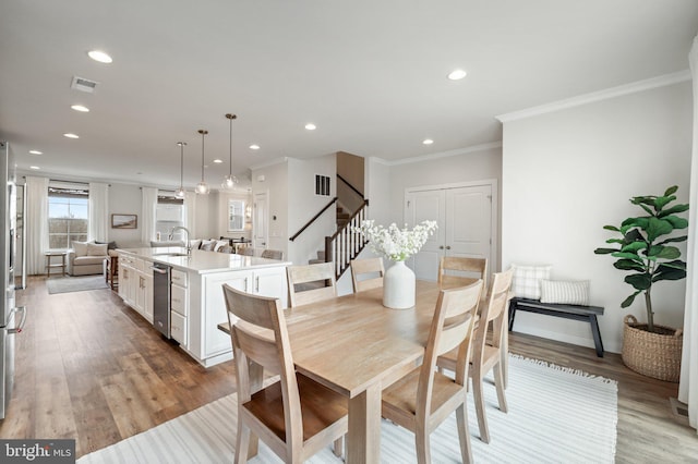 dining room with light wood finished floors, visible vents, ornamental molding, and recessed lighting