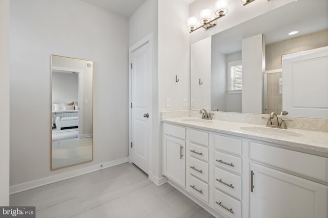 bathroom with connected bathroom, a sink, baseboards, and double vanity