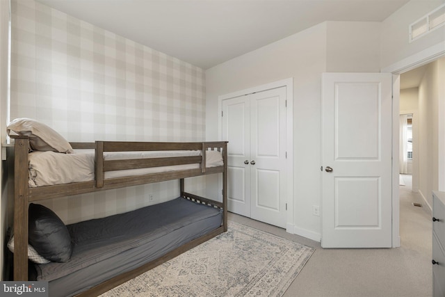 bedroom with a closet, visible vents, baseboards, and wallpapered walls