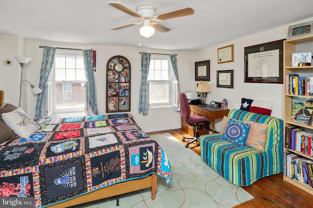 bedroom featuring hardwood / wood-style flooring, ceiling fan, and multiple windows