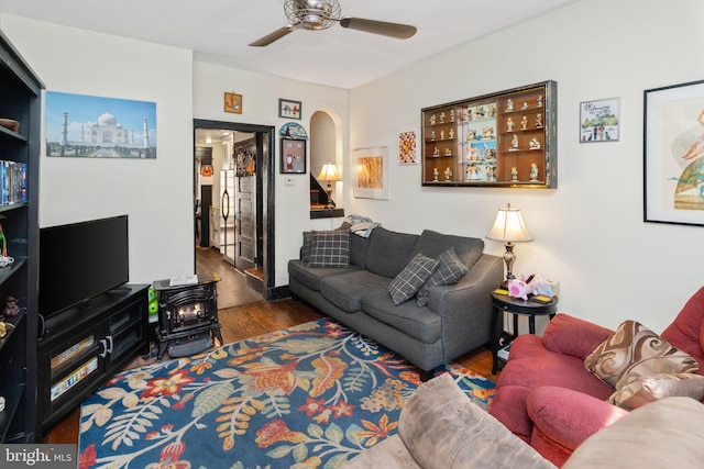 living room featuring ceiling fan, a wood stove, and dark hardwood / wood-style floors