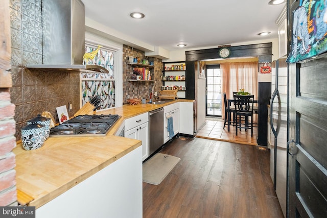 kitchen with butcher block counters, white cabinetry, dark hardwood / wood-style flooring, stainless steel appliances, and exhaust hood