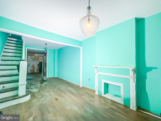 unfurnished living room featuring concrete floors and stairway