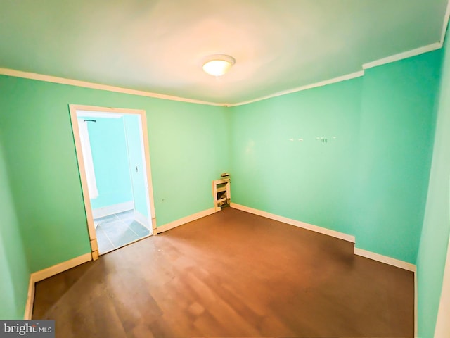 empty room featuring crown molding, baseboards, and wood finished floors