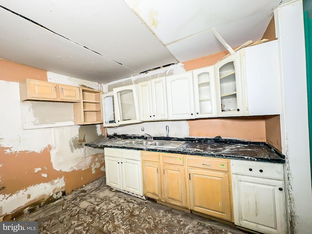 kitchen featuring glass insert cabinets, dark countertops, and a sink