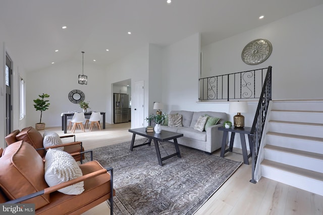 living area with high vaulted ceiling, stairway, light wood-style floors, and recessed lighting