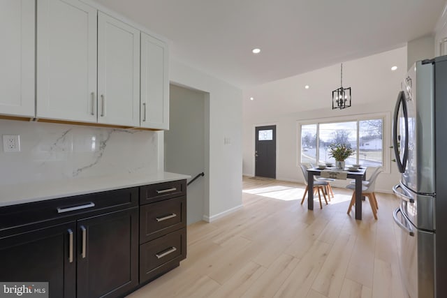 kitchen with light wood finished floors, recessed lighting, decorative backsplash, freestanding refrigerator, and white cabinets