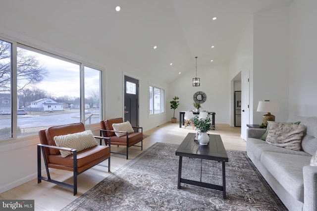 living room with baseboards, high vaulted ceiling, light wood-type flooring, and recessed lighting