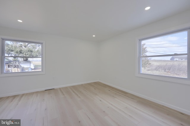 spare room featuring recessed lighting, light wood-style flooring, and baseboards