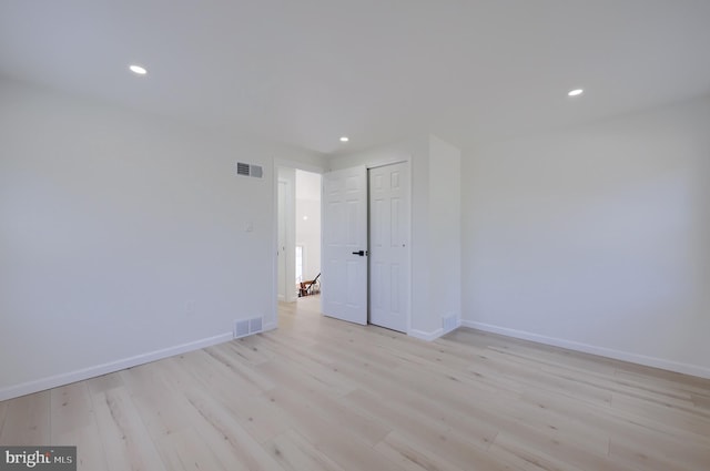 unfurnished room featuring light wood-style floors, visible vents, and baseboards