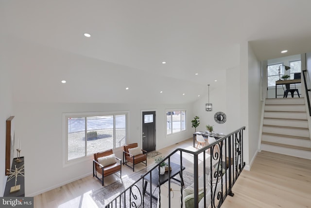 corridor with lofted ceiling, recessed lighting, baseboards, stairway, and light wood-type flooring