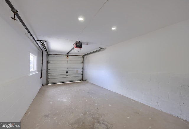 garage featuring concrete block wall and a garage door opener