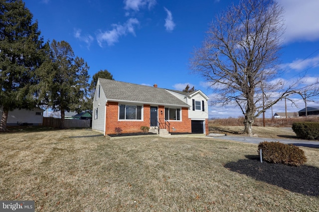 view of front of property featuring a garage, a front yard, fence, and brick siding