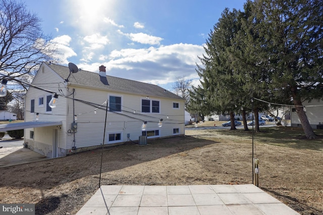 back of property featuring central AC, a chimney, and roof with shingles