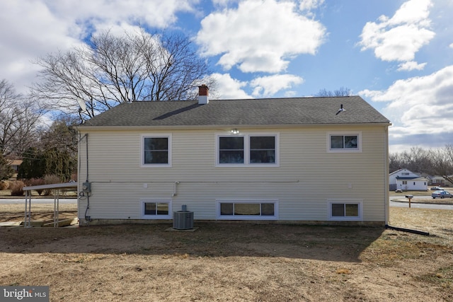 view of side of property featuring roof with shingles, a chimney, and central air condition unit