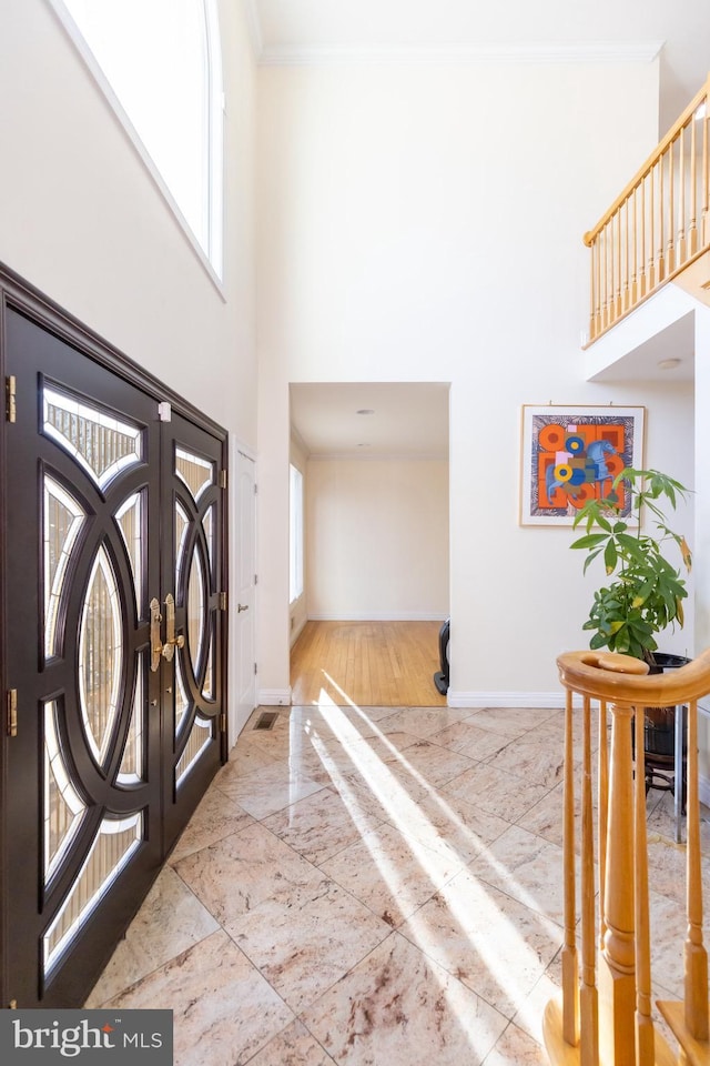 foyer entrance with a towering ceiling and ornamental molding