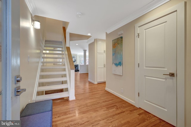 entryway with crown molding, recessed lighting, light wood-style floors, baseboards, and stairs