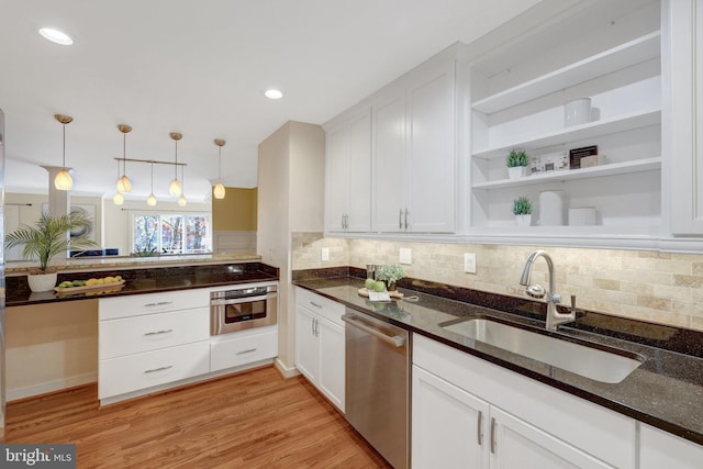 kitchen featuring light wood-type flooring, appliances with stainless steel finishes, white cabinets, and a sink