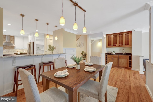 dining space with light wood-style floors, recessed lighting, ornamental molding, and baseboards