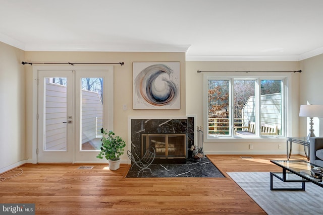 interior space featuring plenty of natural light, wood finished floors, a high end fireplace, and crown molding