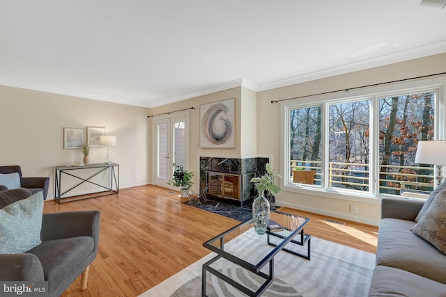 living area with ornamental molding, visible vents, baseboards, and wood finished floors