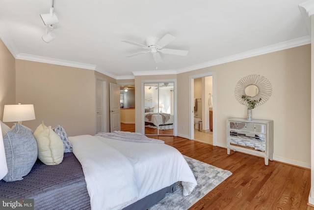 bedroom featuring ceiling fan, connected bathroom, wood finished floors, baseboards, and crown molding