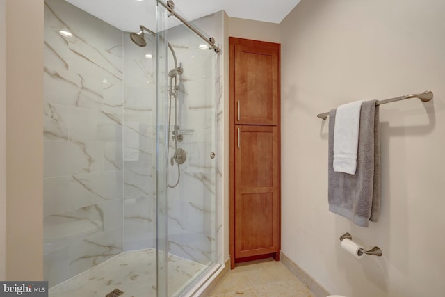 bathroom featuring baseboards, a marble finish shower, and tile patterned floors