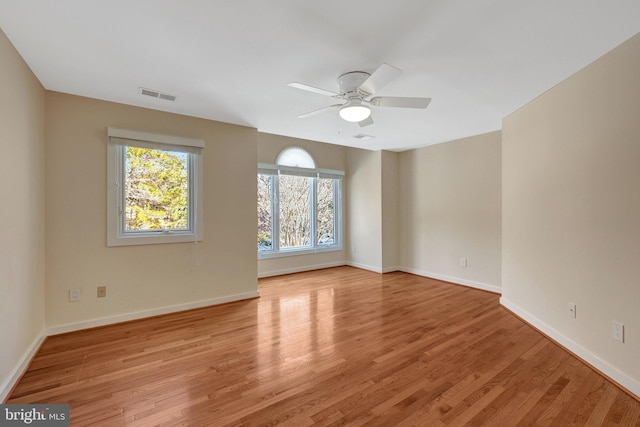 empty room with visible vents, ceiling fan, light wood-style flooring, and baseboards