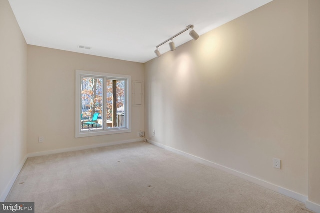 empty room with carpet floors, rail lighting, visible vents, and baseboards