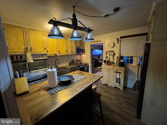 kitchen featuring pendant lighting, sink, wooden counters, stainless steel appliances, and dark wood-type flooring