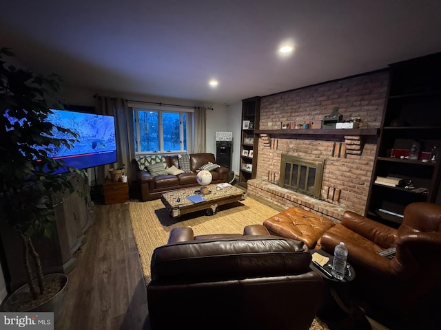 living room with built in shelves, a fireplace, and hardwood / wood-style floors